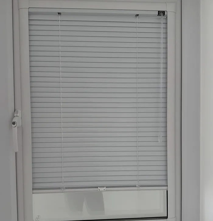 White Perfect Fit Venetian blind clipped inside a uPVC door frame.