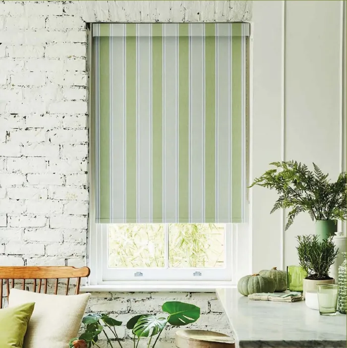 Green and cream striped roller blind fitted in a kitchen window.