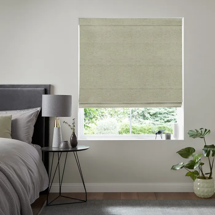 Soft green Roman blind with neat horizontal folds above a bedroom window.