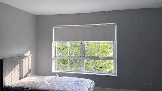 Bedroom with a white blackout roller blind fitted inside the window recess.