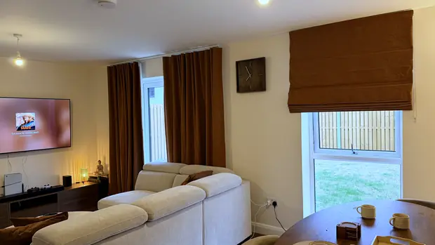 Living room with two rust Roman blinds and matching curtains framing the windows.