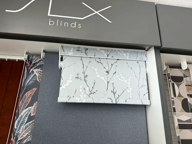Lux Blinds branded sample display showing roller, Roman and patterned fabric options.